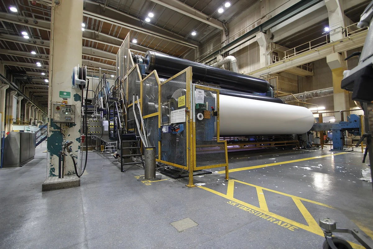 Large roll of raw paper mounted in a full-size paper production machine